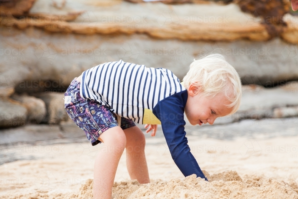 Cute little boy playing in the sand at the beach - Australian Stock Image