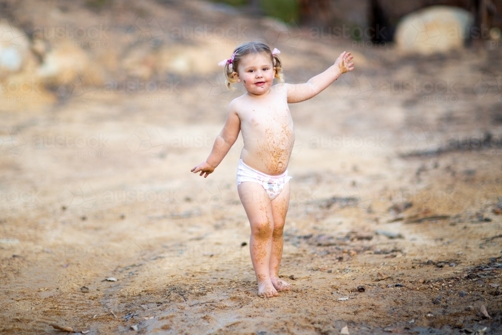 Cute little girl playing in mud - Australian Stock Image