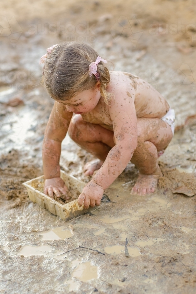 Cute little girl playing in mud - Australian Stock Image