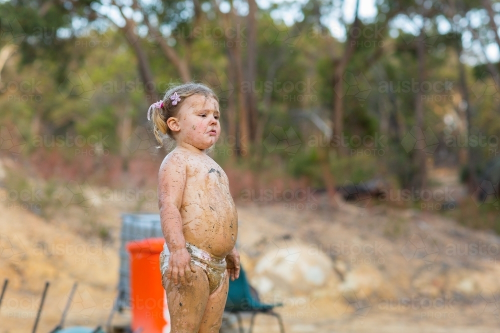 Image of Cute little girl playing in mud Austockphoto