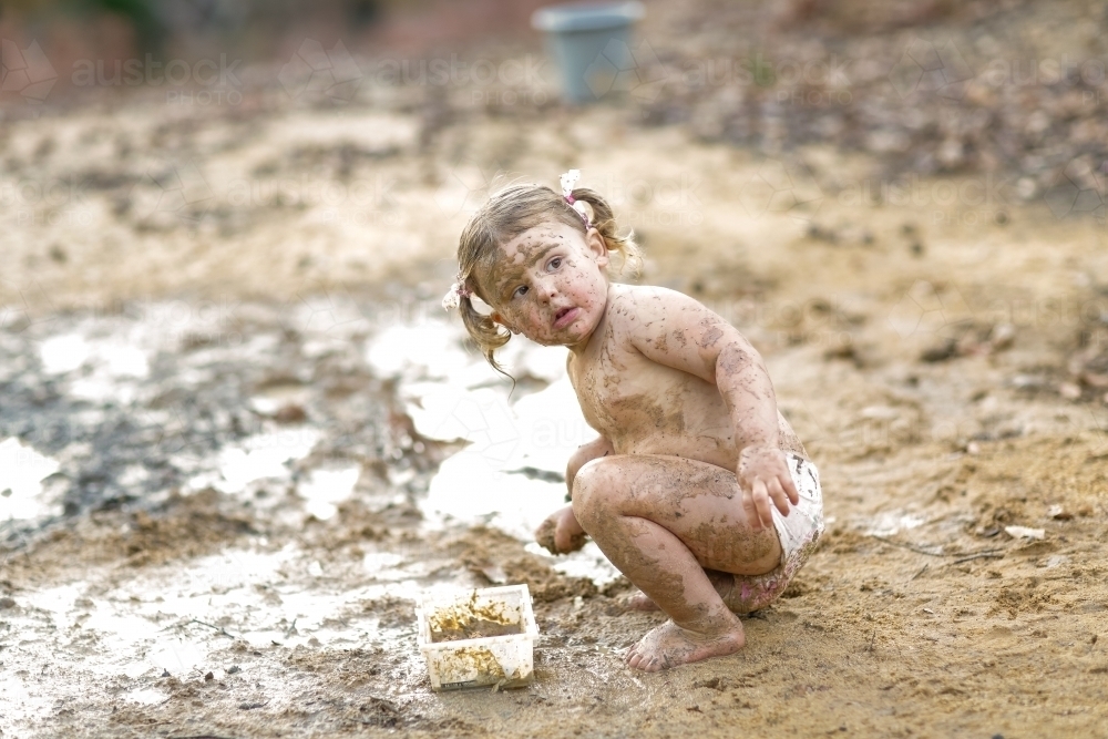 Cute little girl playing in mud - Australian Stock Image