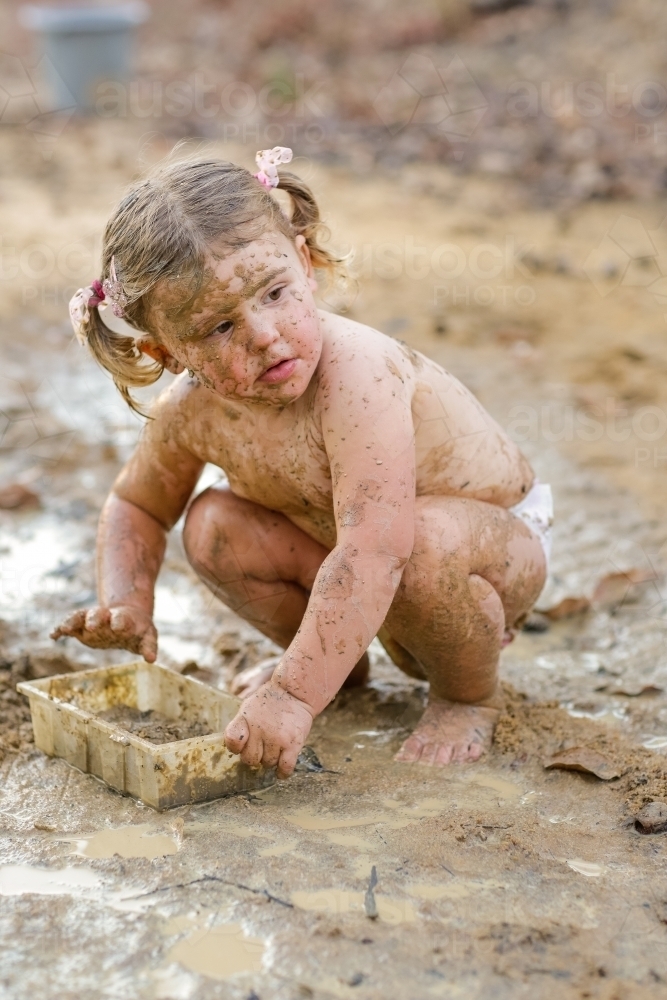 Cute little girl playing in mud - Australian Stock Image