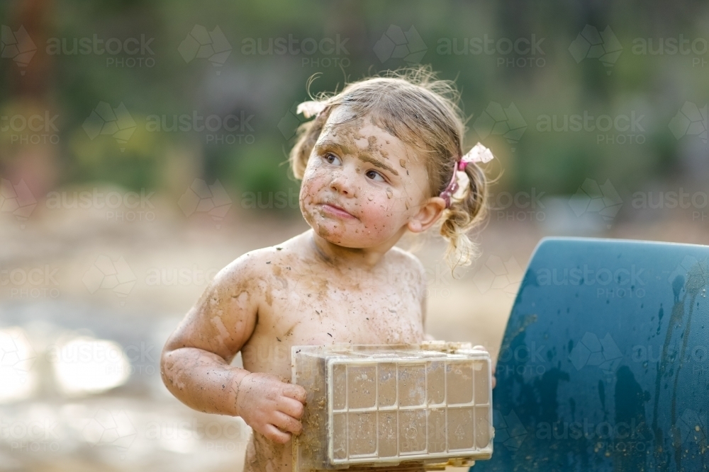 Cute little girl playing in mud - Australian Stock Image