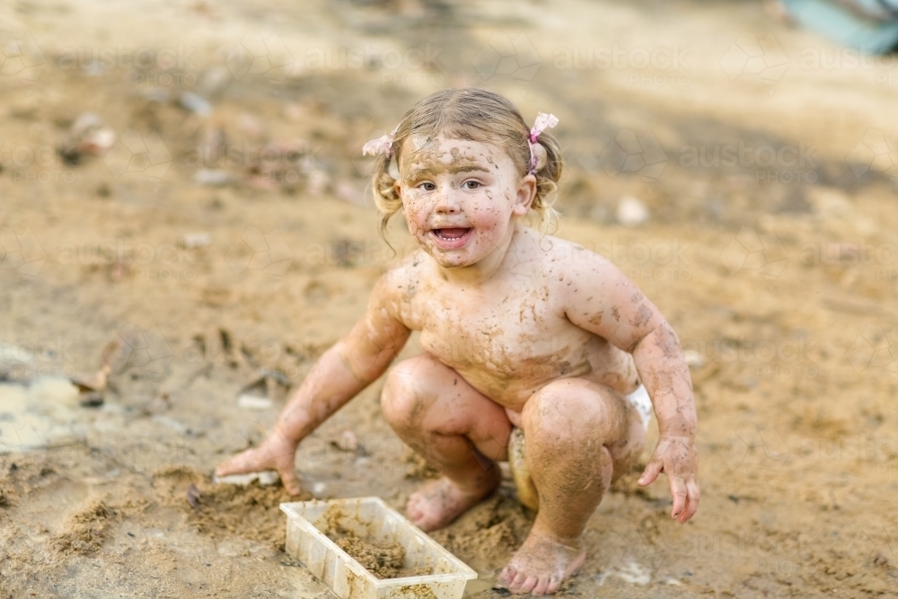 Cute little girl playing in mud - Australian Stock Image