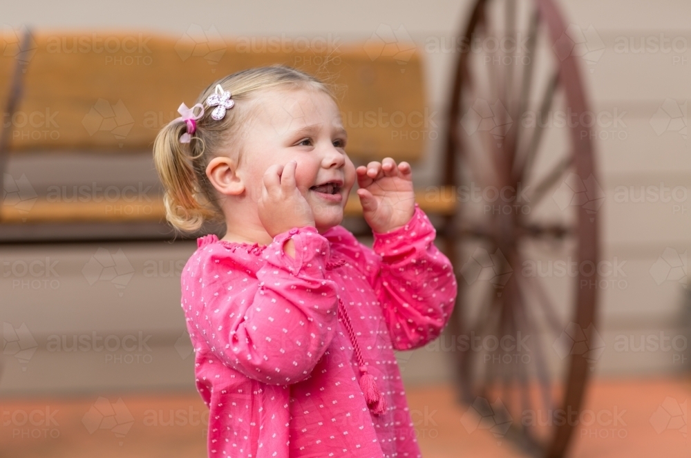Cute little girl twirling with hands up to face - Australian Stock Image