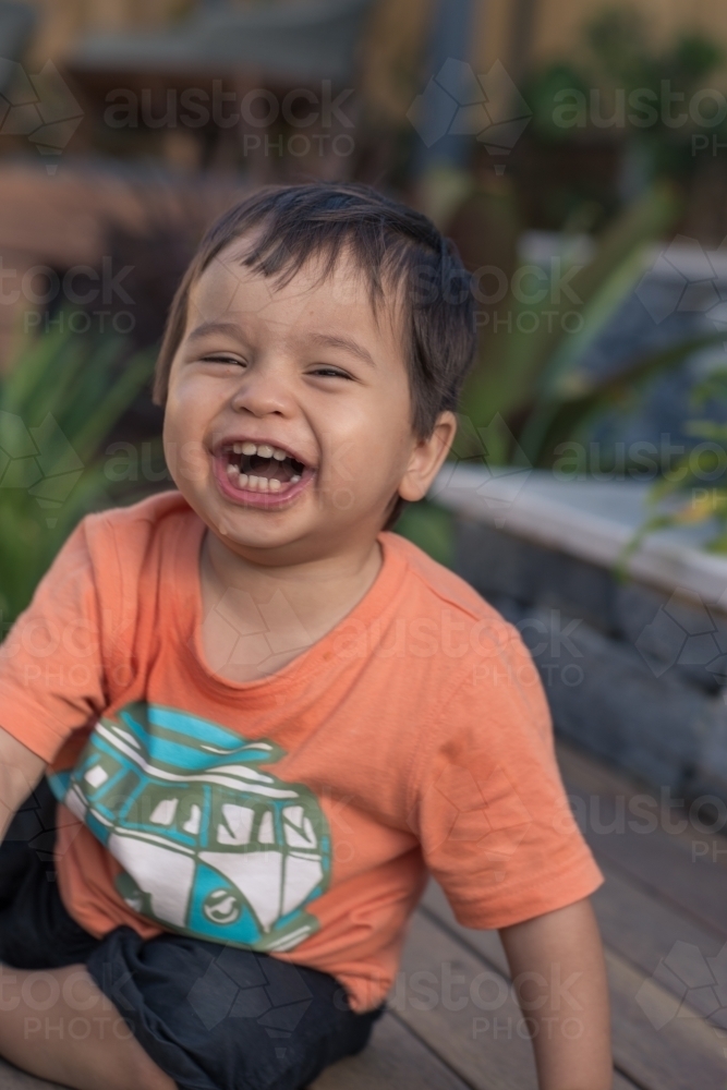 Cute mixed race 1 year old baby boy plays happily in his suburban backyard - Australian Stock Image
