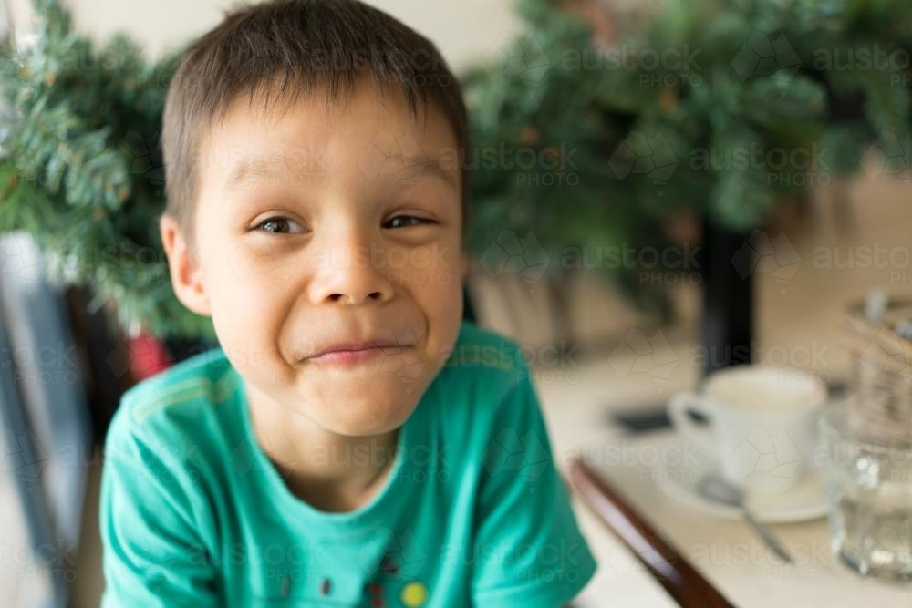 Cute mixed race boy drinking a babychinno in a neighbourhood cafe - Australian Stock Image