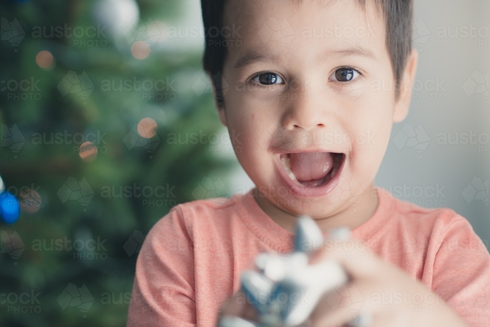 Cute mixed race boy hanging decorations on their Christmas tree - Australian Stock Image