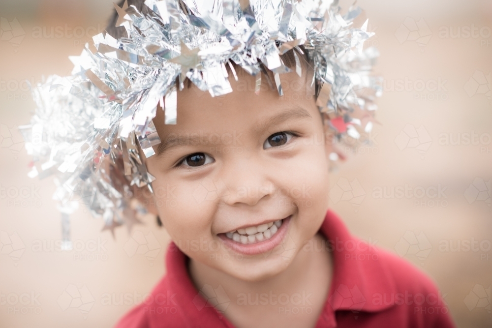 Cute mixed race boy looking angelic with Christmas tinsel on his head - Australian Stock Image