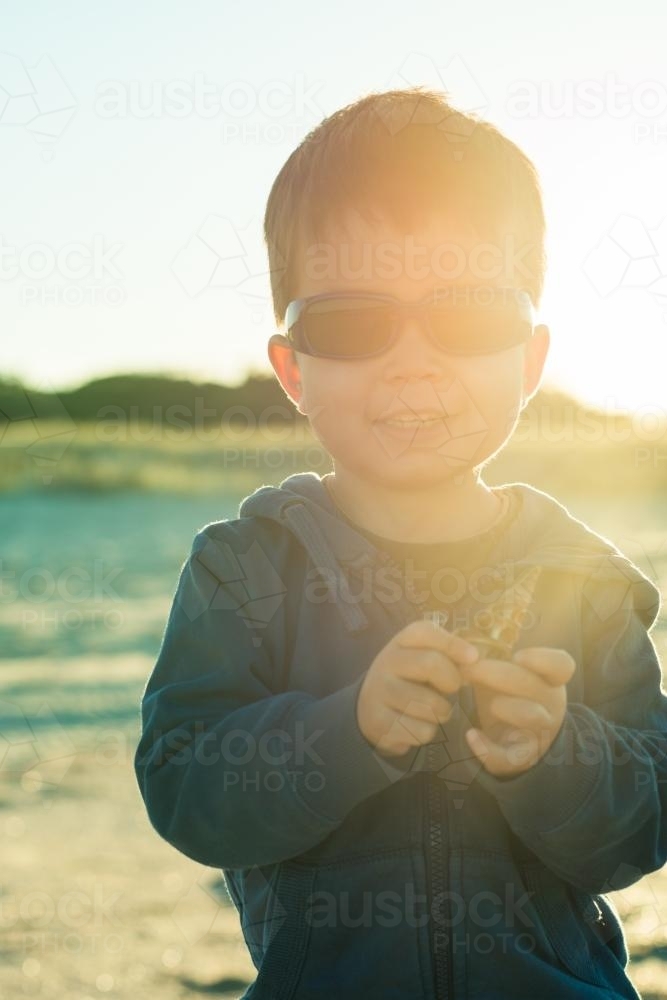 Cute mixed race boy on a beach on a sunny winter day - Australian Stock Image