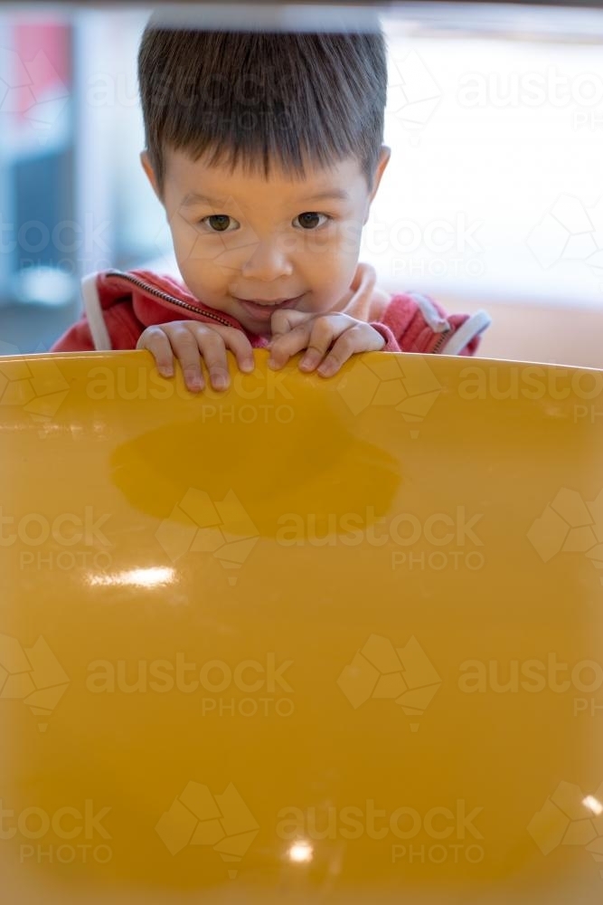 Cute mixed race boy plays with a charity donation coin vortex - Australian Stock Image
