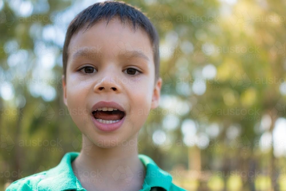 Cute mixed race boy talking outside - Australian Stock Image