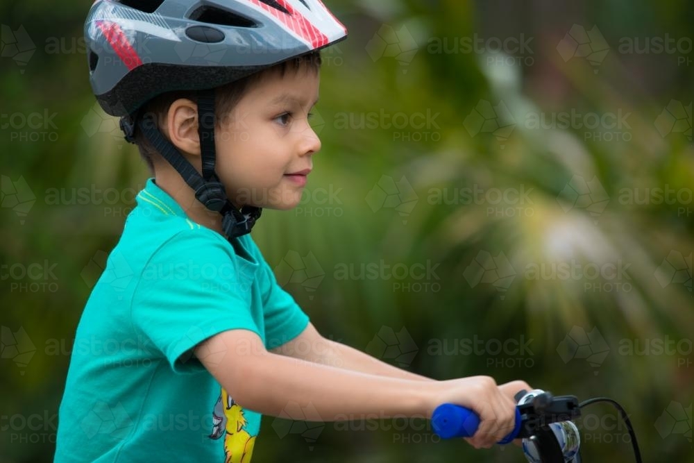 Cute mixed race boy wearing a helmet and riding his bike - Australian Stock Image