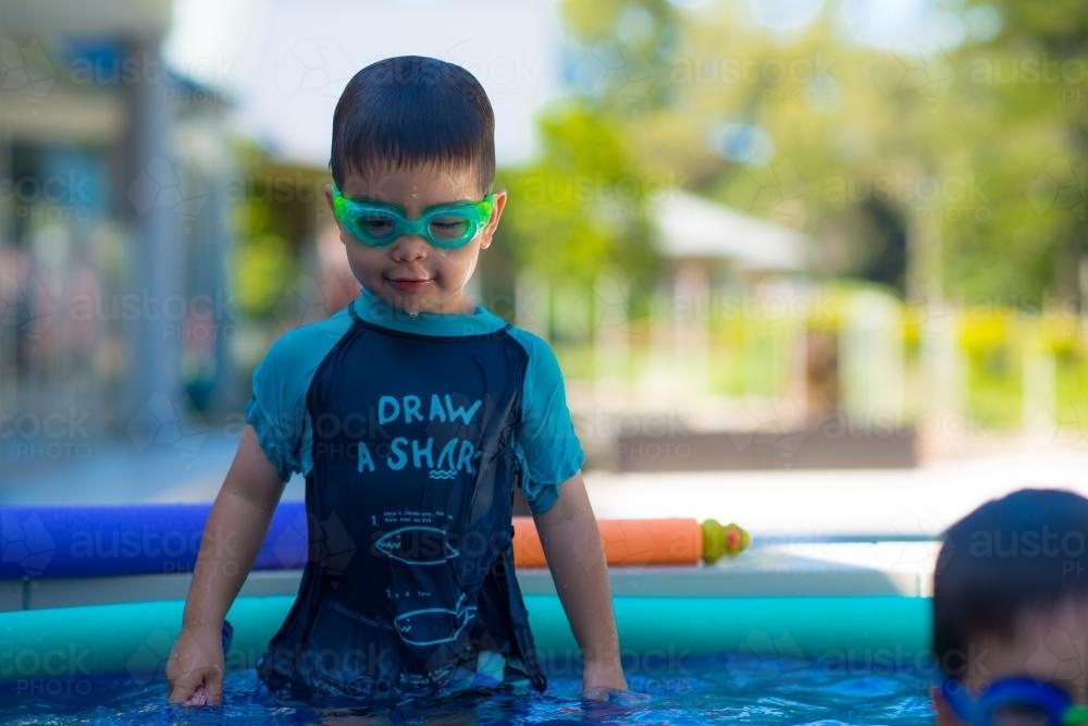 Cute mixed race boys play in the bubbles of a backyard spa - Australian Stock Image