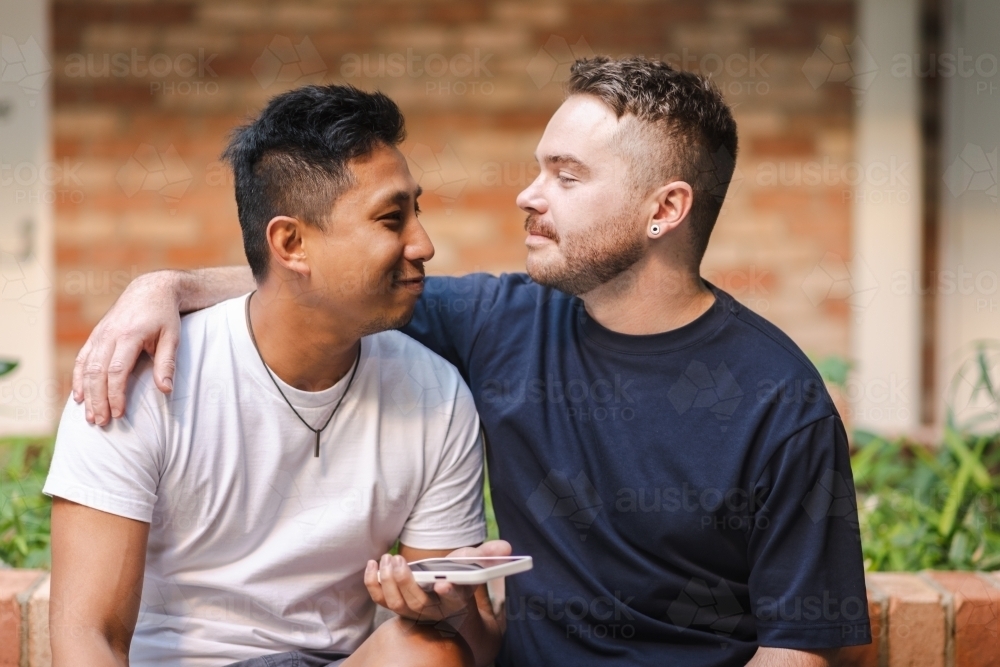 cute moments as gay couple look at their phone - Australian Stock Image