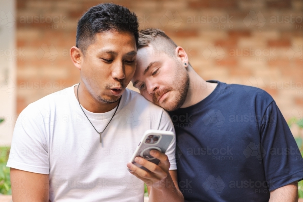 cute moments as gay couple look at their phone - Australian Stock Image