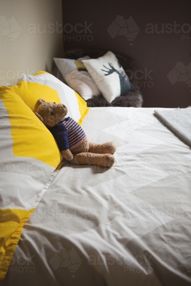 Cute toy teddy bear on the bed in a vintage styled guest bedroom - Australian Stock Image