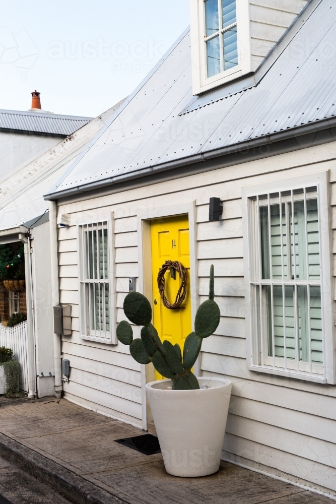 Cute white weatherboard cottage with yellow door and cactus in paddington, sydney - Australian Stock Image