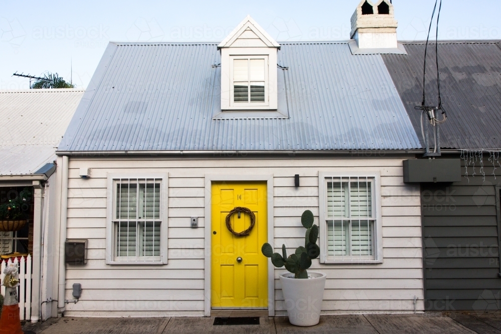 Cute white weatherboard cottage with yellow door and cactus in paddington, sydney - Australian Stock Image