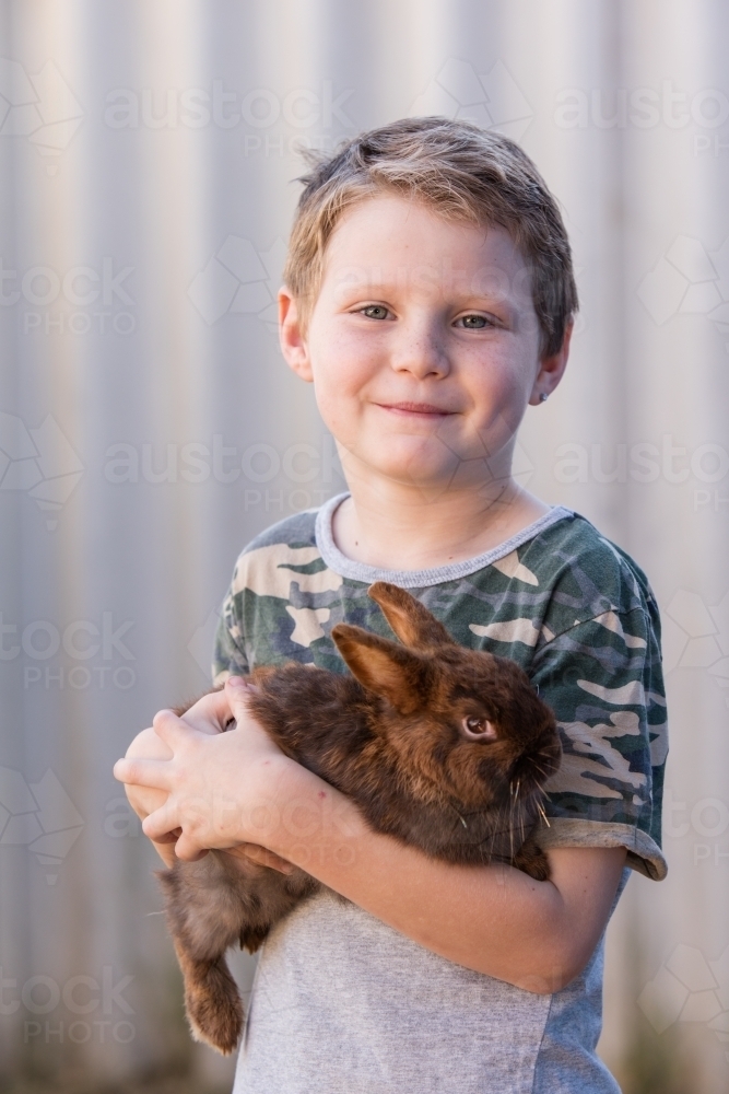 Cute young boy holding pet bunny - Australian Stock Image
