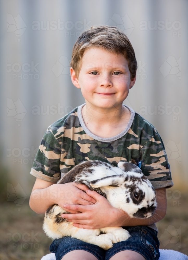 Cute young boy holding pet bunny - Australian Stock Image