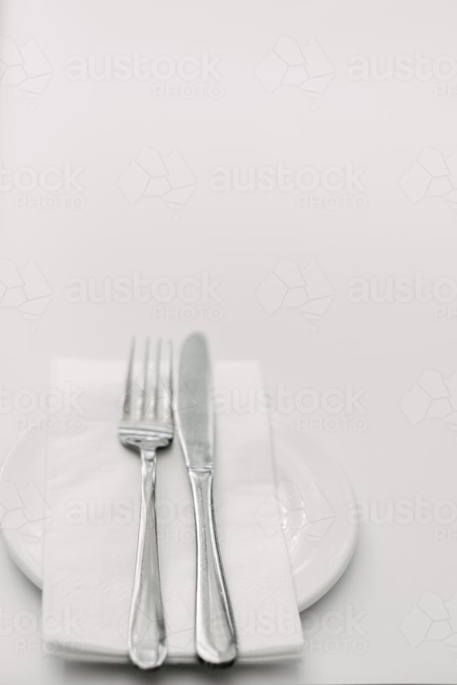 cutlery with napkin on a plate against a white background - Australian Stock Image