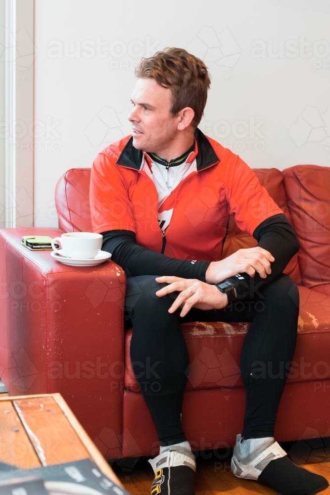Cyclist enjoying a coffee after a morning ride - Australian Stock Image
