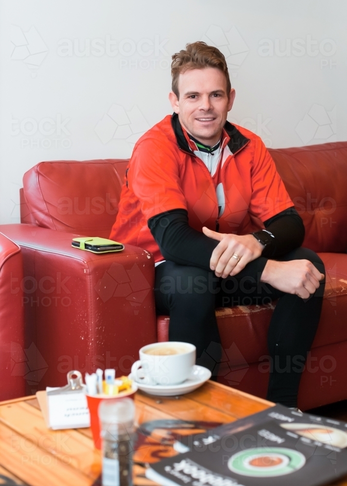 Cyclist enjoying a coffee at a cafe after a morning bike ride - Australian Stock Image