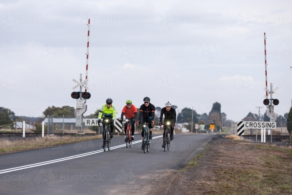 Cyclist riding across a rail crossing in the early morning - Australian Stock Image