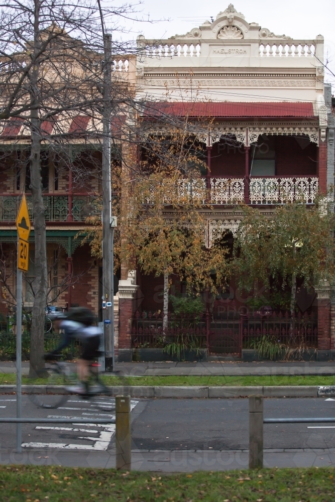 Cyclist riding down a street in city inner suburbs. - Australian Stock Image
