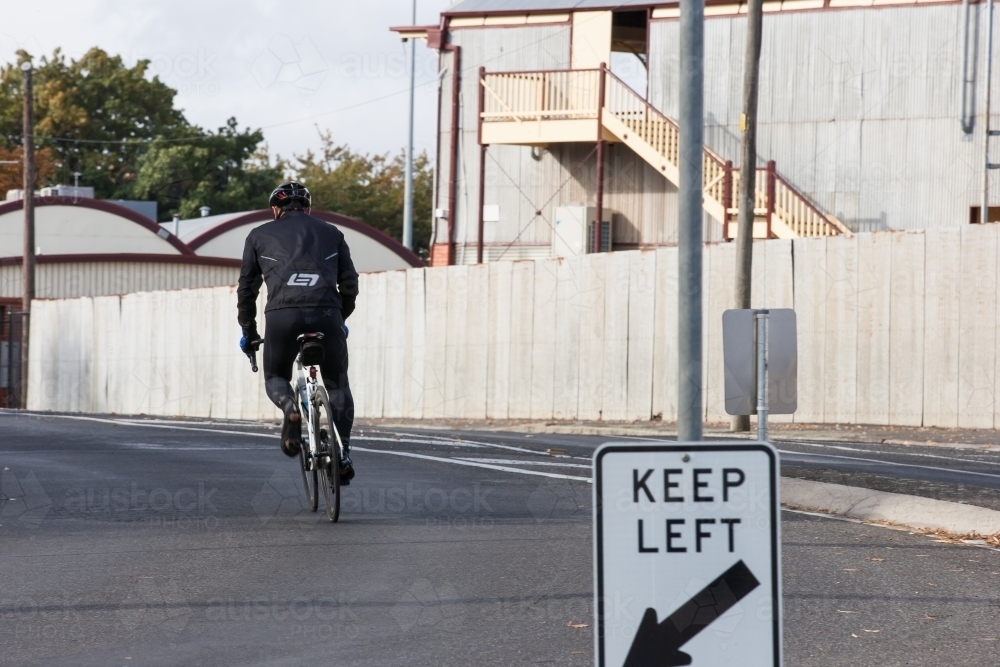 Cyclist riding in the middle of the road in the city - Australian Stock Image