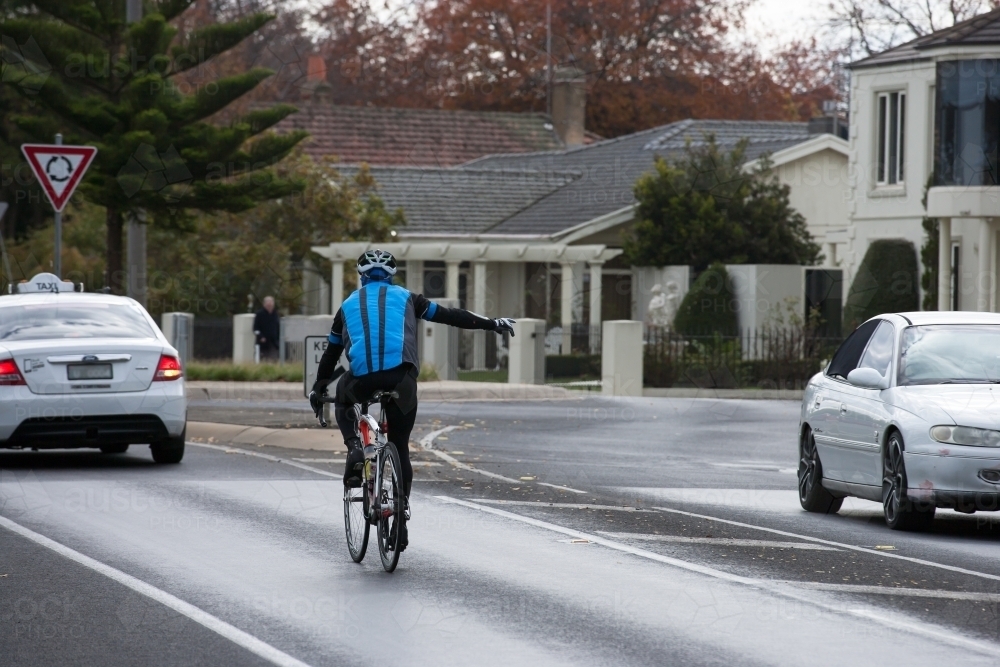 cyclist signaling as he approaches a roundabout - Australian Stock Image