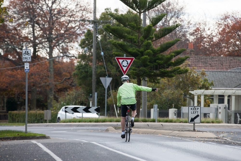 cyclist signaling as he approaches a roundabout - Australian Stock Image