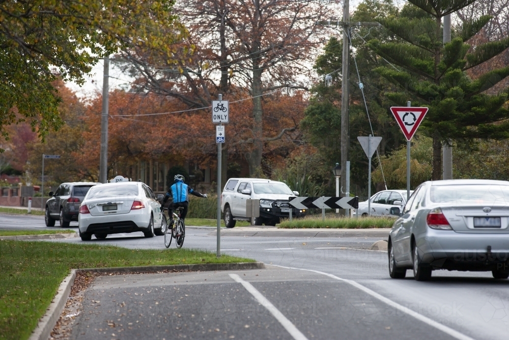 cyclist signaling while turning right in a roundabout - Australian Stock Image