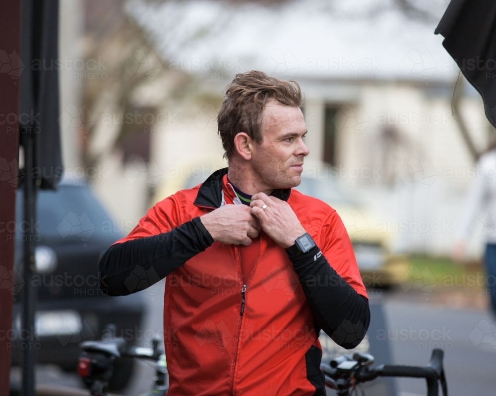 Cyclist unzipping his jacket after a ride - Australian Stock Image