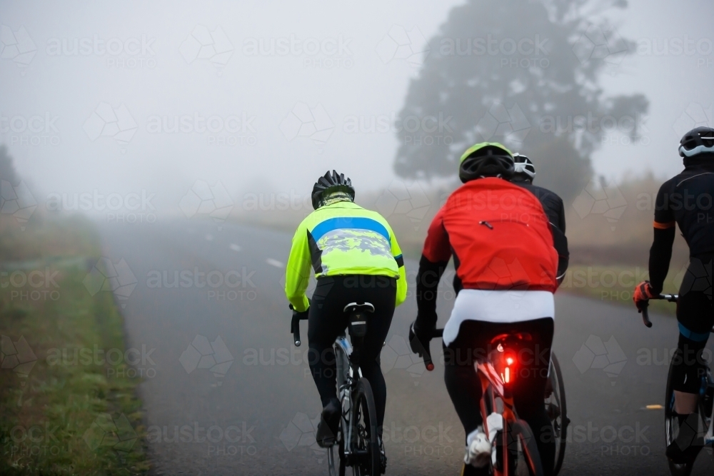 Cyclists riding in a foggy morning on a country road - Australian Stock Image