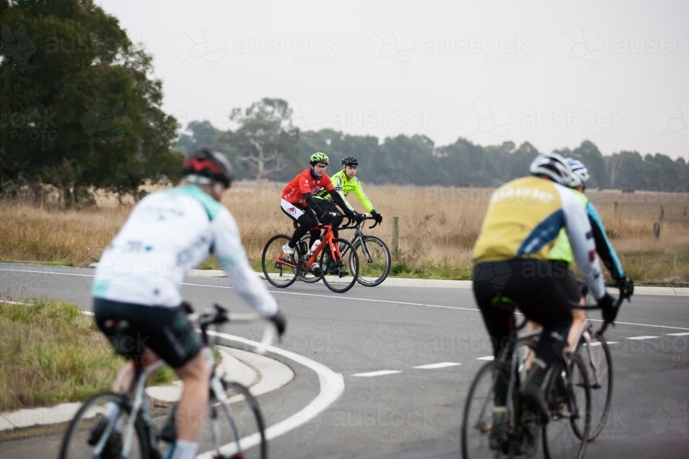 Cyclists waiting at intersection for another group to pass - Australian Stock Image