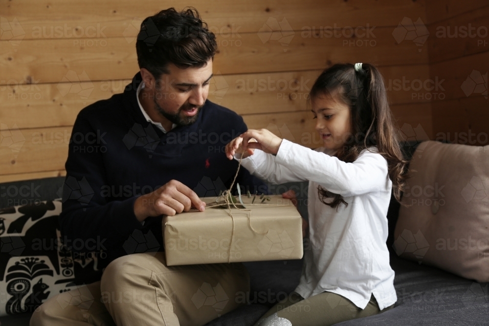 Dad and daughter opening present in lounge room - Australian Stock Image