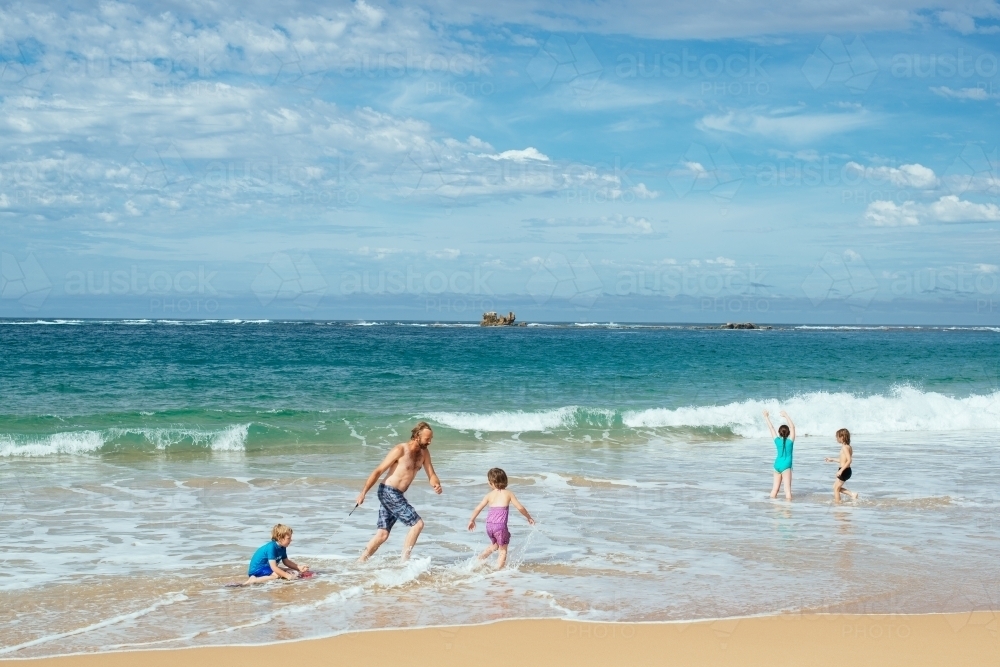 Dad and kids playing at beach - Australian Stock Image