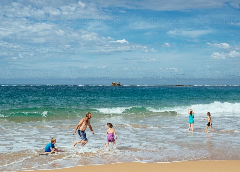 Dad and kids playing in surf - Australian Stock Image