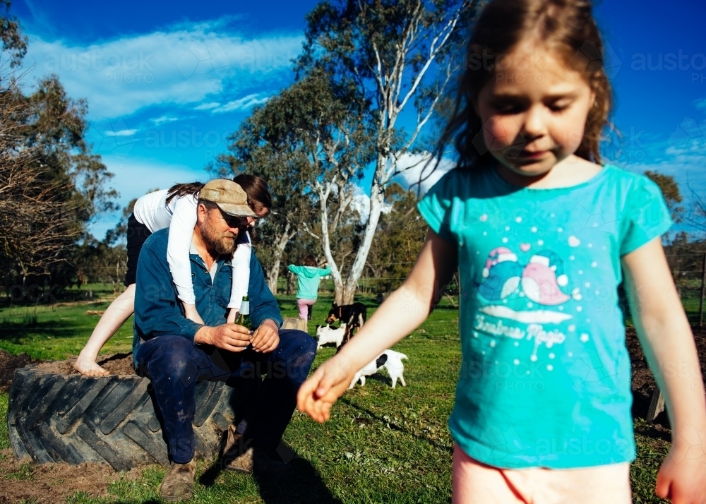 Dad & daughters outside relaxing with dogs in background - Australian Stock Image