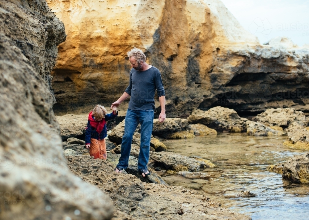 Dad helping son explore Bay of Martyrs - Australian Stock Image