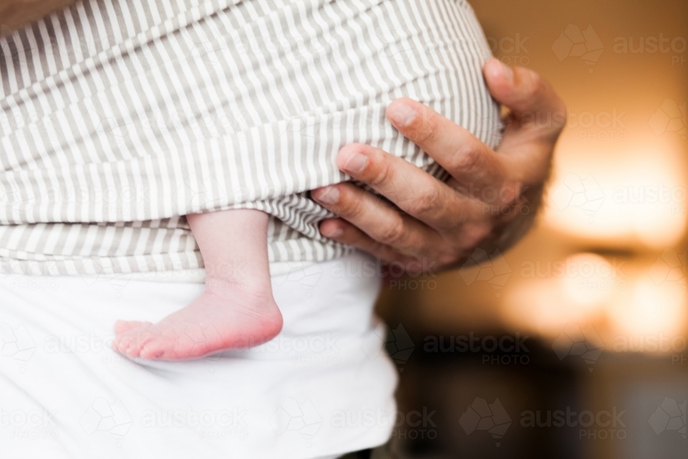 Dad holding baby in wrap with baby foot - Australian Stock Image