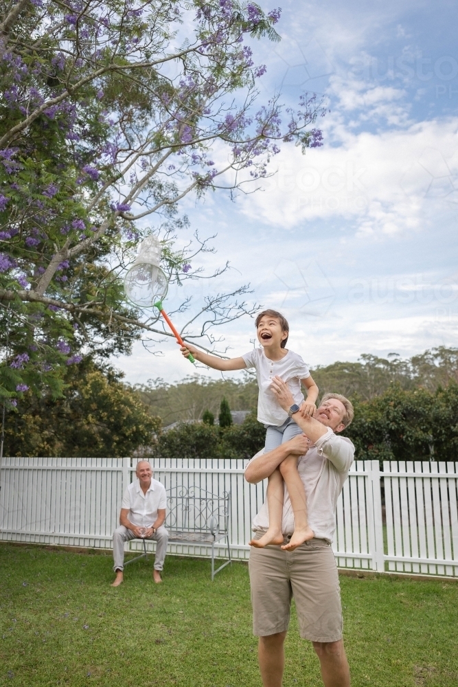Dad holding up son holding butterfly net - Australian Stock Image