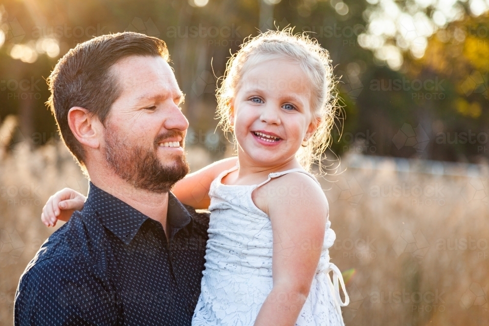 Dad holding youngest daughter outside - Australian Stock Image