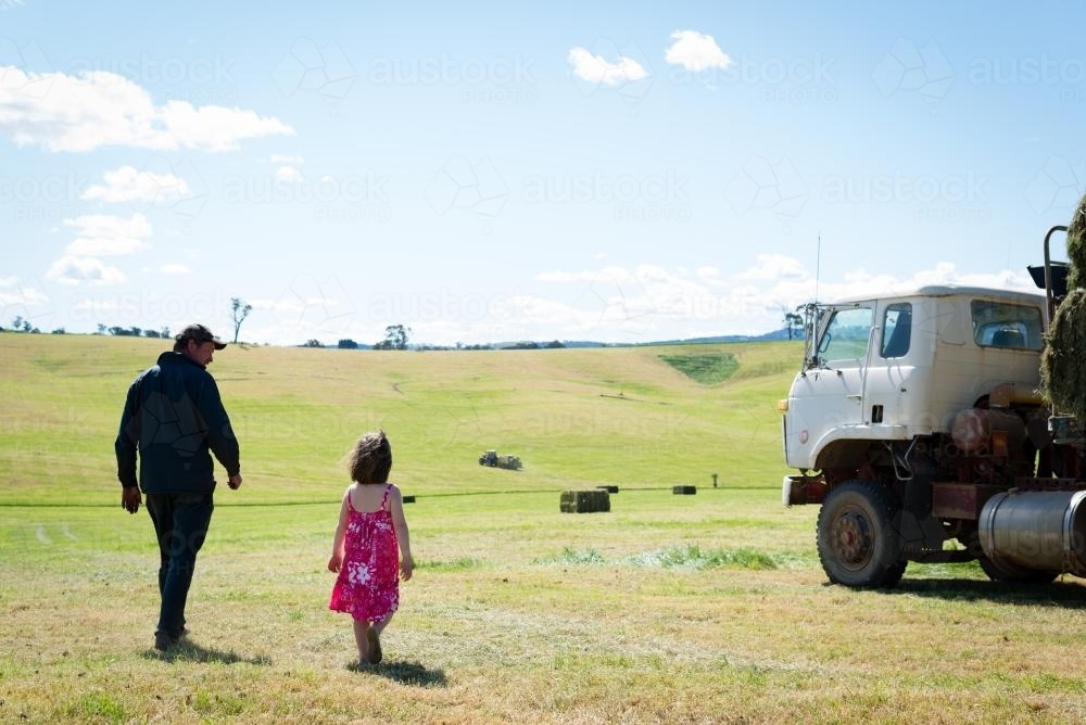 Dad & little girl walking in a hay paddock - Australian Stock Image
