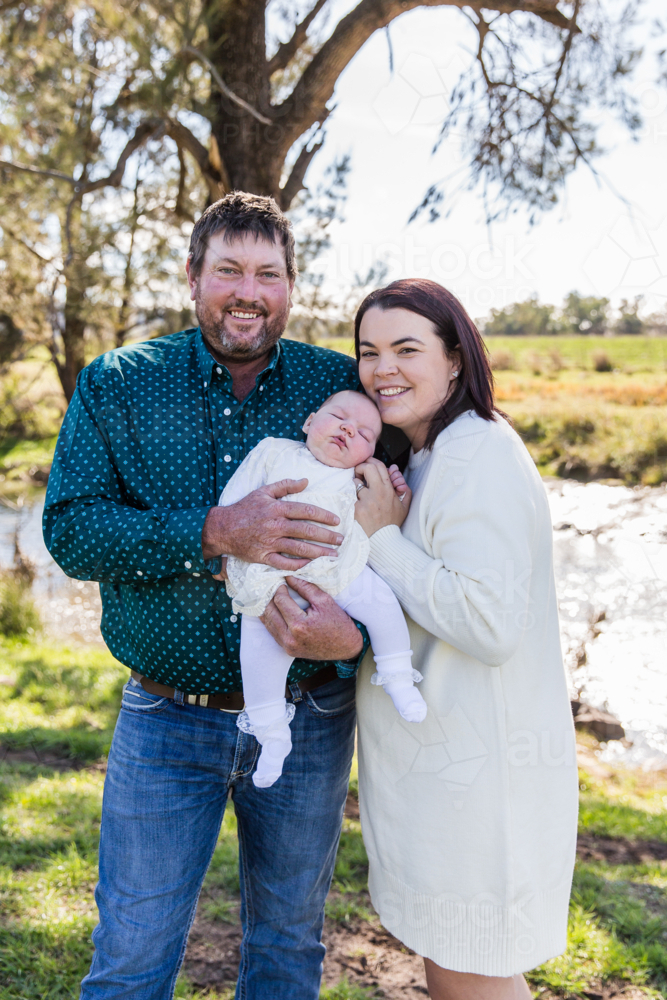 Dad, mum and newborn child cuddling and smiling - Australian Stock Image