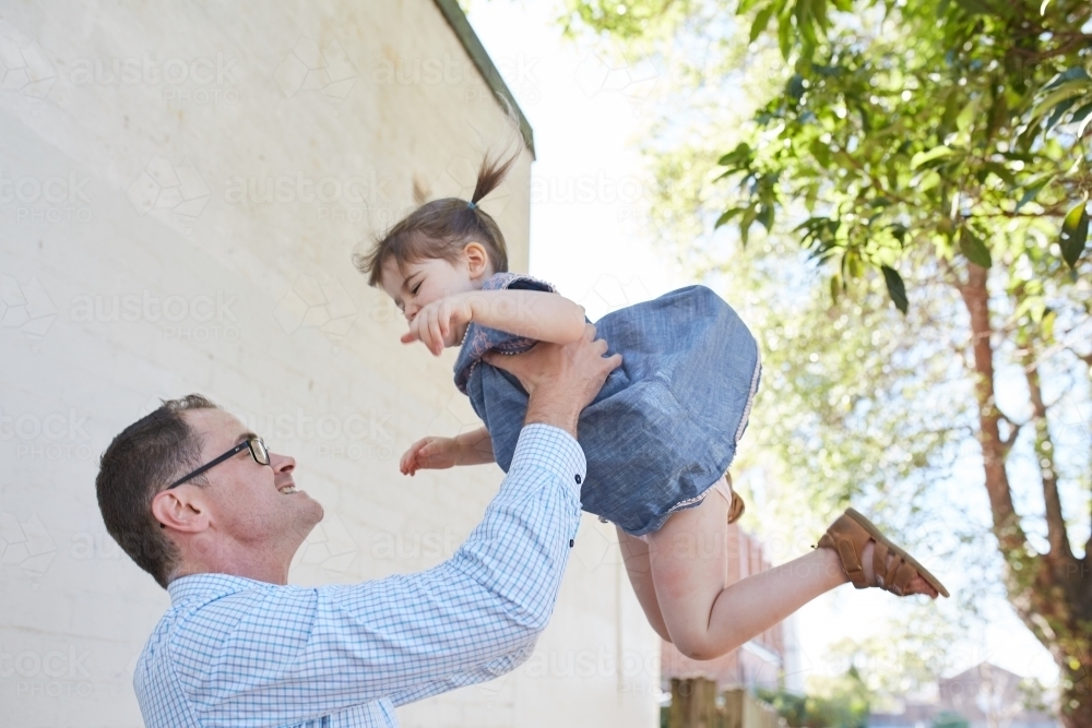 Dad playfully throwing daughter in the air - Australian Stock Image
