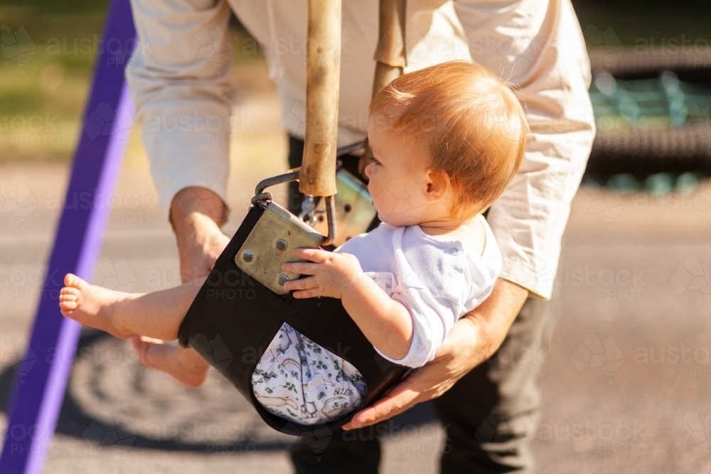 Dad pushing young aussie kid on swing at park in Singleton - Australian Stock Image