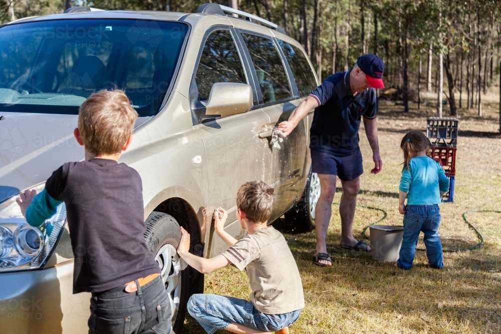Dad washing the family car with his kids - Australian Stock Image